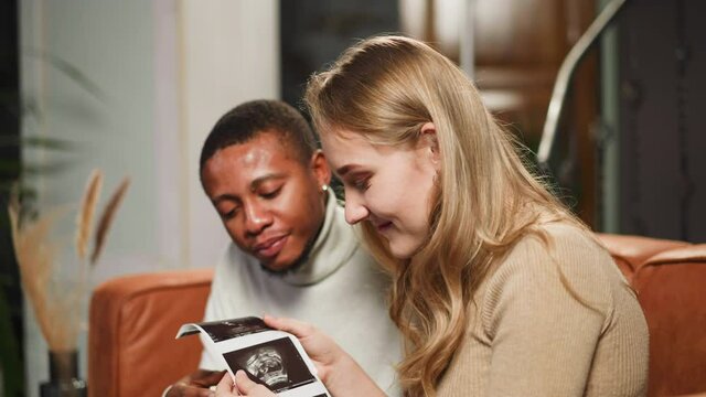 Family of woman and black man looks at ultrasonic photos