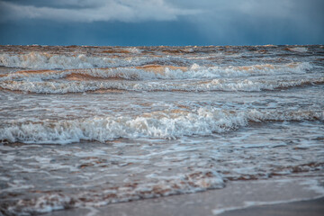 Sunlight shines on the sea waves. The wind blows the waves ashore. In winter, the embankment is icy with stones