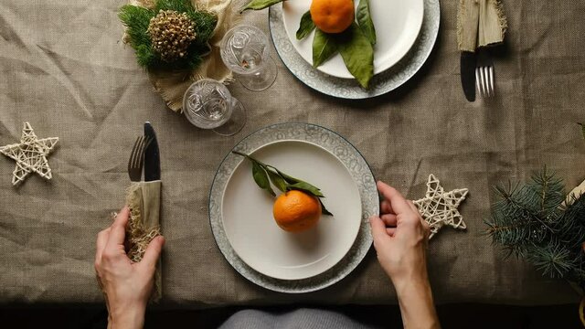 Christmas Table Setting. Woman Puts Two Drinking Glasses On Served Table. Festive Dinner Preparation, Christmas And New Year Celebration Concept. Overhead View, POV.