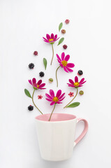 Composition of berries and flowers over a cup.