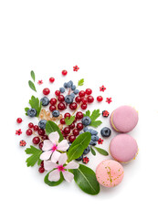 A scattering of juicy berries, flower and macarons.