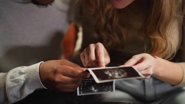 White woman shows baby on ultrasound pictures to husband