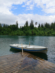 Boat by a pier on Caumasee lake surrounded by trees - Flims, Switzerland