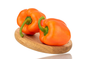 Two ripe orange sweet peppers on a wooden tray, close-up, isolated on white.