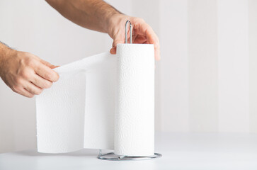 an anonymous hand is tearing off paper towel, hygiene concept copy space includes.