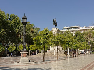 Fototapeta na wymiar Plaza Nueva square, with equestrian monument of Fernando III , lanterns and trees in Seville, Andalucia, Spain 