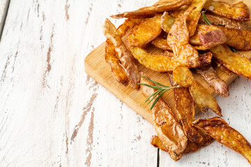 Fried potato peel with rosemary on a white wooden table close-up free space. Sustainable food.