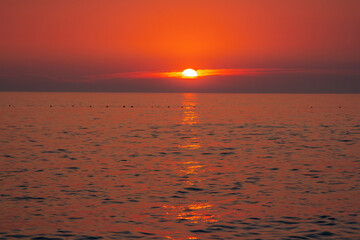 Beautiful landscape - beach on sunset -red and orange sky and sunlight reflecting on sea water.