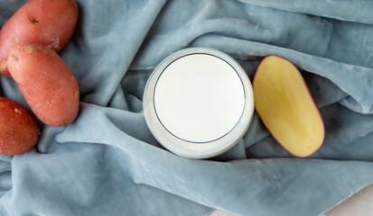 Milk from potatoes in a glass on a background of fabric, top view.