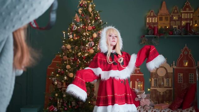 Cute girl in a red costume of the New Year's elf. Posing for the photographer. New Year theme