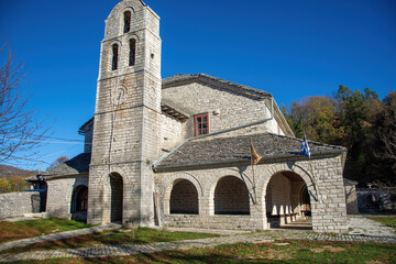 Traditional architecture with narrow stone road and Agios Athanasios stone built church during fall season in the stone village Monodendri central Zagori Greece
