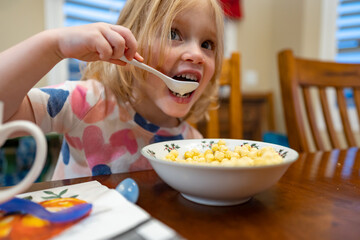 Little girl hungerly eating breakfast cereal