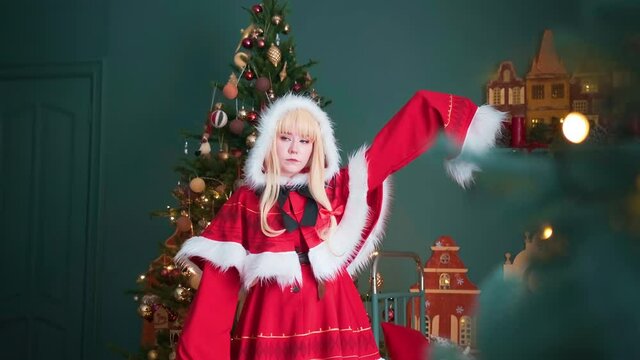 Cute girl in a red costume of the New Year's elf. Posing for the photographer. New Year theme