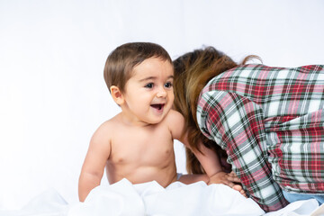 Baby boy in a studio with a white background, eight month old Caucasian newborn sitting and playing with his mother
