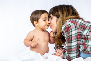Baby boy in a studio with a white background, eight month old Caucasian newborn sitting and playing with his mother