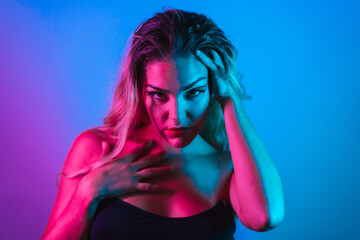 A Caucasian blonde girl in a black t-shirt with eye drawing makeup, eyelashes arranged on a blue background with pink neon lights