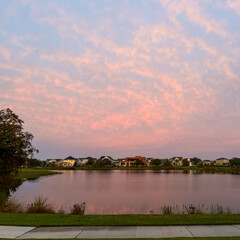 Obraz premium Beautiful pink, orange and blue sunset reflecting on a lake in a suburban neighborhood.