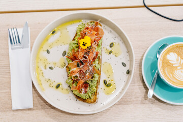avocado and ham toast and cup of coffee at work space