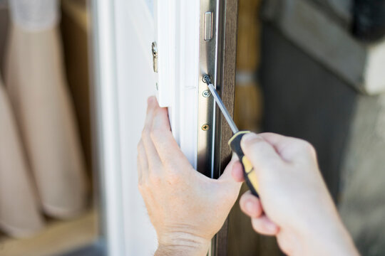 Handyman installing lock in plastic front door. Checking lock for operability.