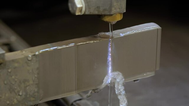 Automatic wire cutting machine working with metal workpiece with sparks at factory, exhibition, plant - close up. Metalworking, industrial, machining, technology, manufacturing and equipment concept