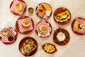 Table with Latin American food, Venezuelan Arepas, empanadas, platano with cheese. - obrazy, fototapety, plakaty