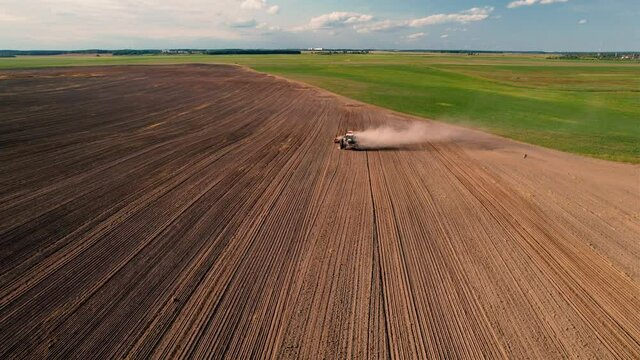 Tractor sowing seed onto at field. Planting Equipment and Farm Implements and Machine. Mini Agricultural tractor on seeds sowing at farmers country, aerial view. Farming and seeding concept.