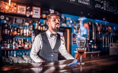 Experienced bartending mixes a cocktail while standing near the bar counter in nightclub