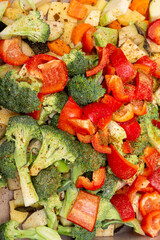 An original background of finely chopped and seasoned vegetables before baking in the oven. Potatoes, bell peppers, squash, pumpkin and broccoli. Healthy food close-up