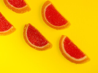 Fruit jelly in the form of grapefruit slices on a yellow background. Sweets on the table. Background from marmalade.