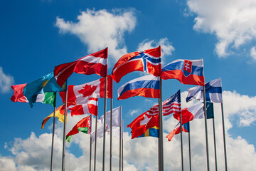 Flags of different European countries against the blue sky and clouds