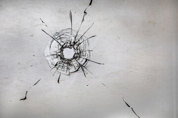 Bullet hole in dirty glass on a white background.