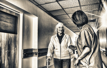 Asian female doctor reassuring mature elderly woman with walker. Two women smiling happy in the...