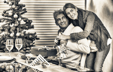 Happy smiling young couple embracing in front of Christmas tree for Christmas.