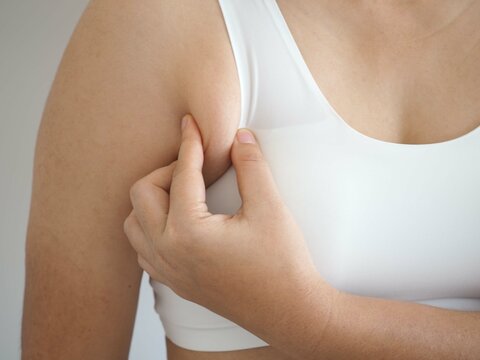 Asian woman pulling her skin underarm. problem armpit fat skin concept. closeup photo, blurred.
