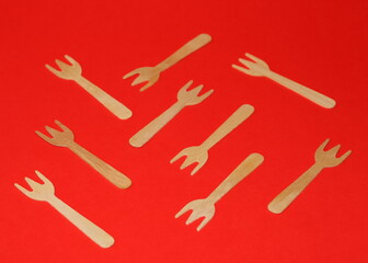 Ecological single use wooden forks on red background