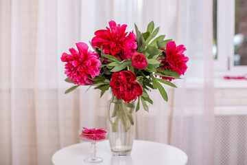 Bouquet of beautiful pink peonies flowers in vase on table near window
