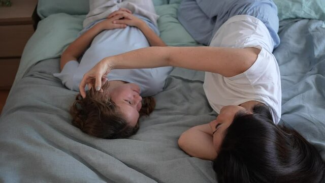 Happy mother and her teenage daughter talking in bed. Concept of happy family, mother and daughter, mother's day, relaxing moments.