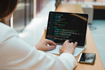A freelance programmer works remotely, a young woman sits at a table in a coworking or business...