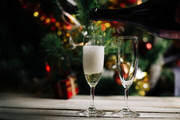 champagne is poured into glasses against the background of the Christmas tree, celebration of the new year