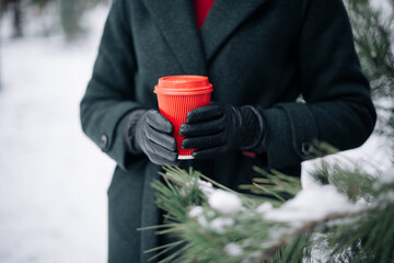 a cup of hot takeaway coffee in the hands of a young woman in winter