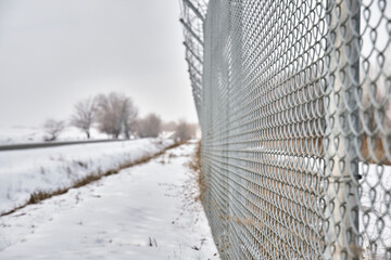 Close up of barbed wire fence on border in winter. Private secured object near highway. Maximum security detention facility. Closing for quarantine. Unauthorized entry is prohibited.