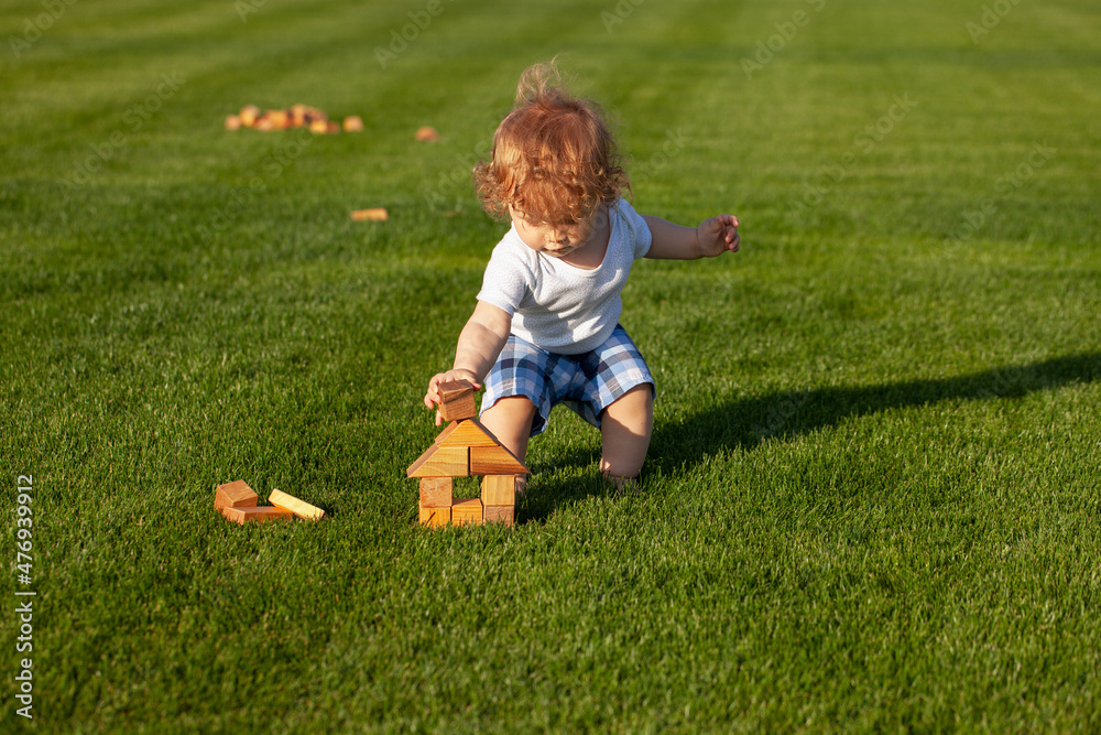 Wall mural Little child play in park. Portrait of a happy baby in grass field.