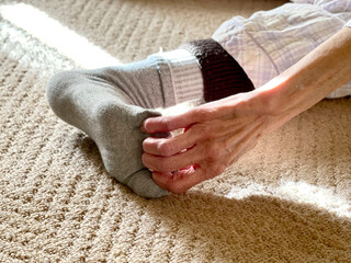 靴下を履いた足の指を引っ張る高齢女性の手