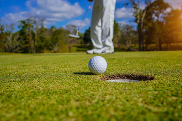 Golf clubs and golf balls on a green lawn in a beautiful golf course with morning sunshine. golf ball on green grass ready to hit on golf course background