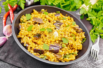 Bulgur with eggplant in pan on black board