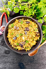 Bulgur with eggplant in pan on dark board top