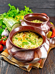 Rice with chicken and vegetables in two pots on towel