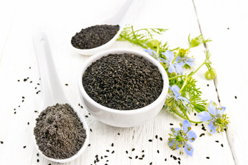 Seeds of black cumin in bowl on light board