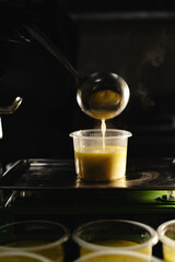 Food delivery in the restaurant. The chef prepares and prepares food in disposable dishes on a scale weighing the required portion. Close-up of a ladle poured soup into a lunch box.