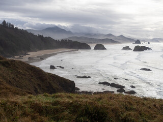 Fototapeta na wymiar Overlook of the Oregon Coast with Sandy Beach, Sea Stacks, and Distant Mountains